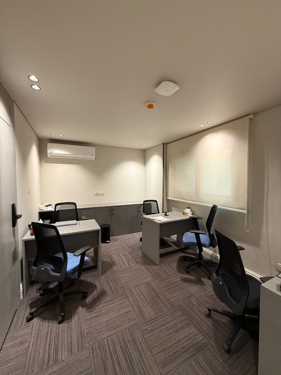 Breakout room with desks, ergonomic chairs and a projection screen