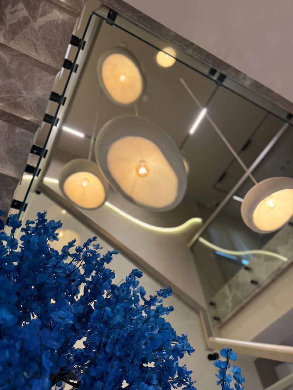 Pendant lights above the stairwell, framed by blue blossoms