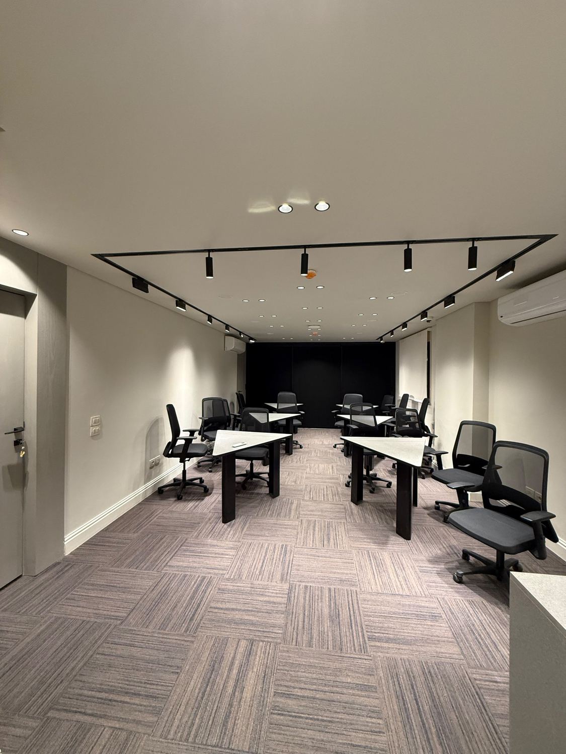 Training hall with track lighting, modular tables and a feature wall